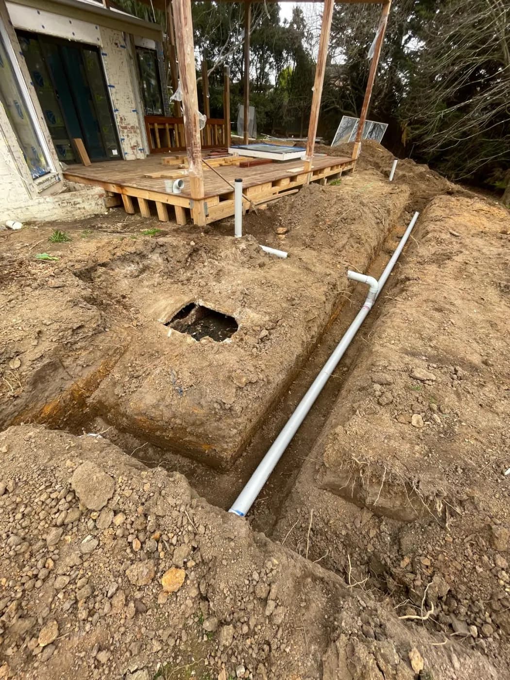 Excavation alongside the house, exposing the drainage and a soak pit