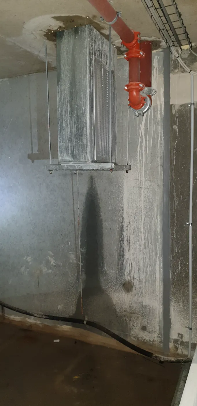 The basement wall below the fire services pipework, with water standing on the floor