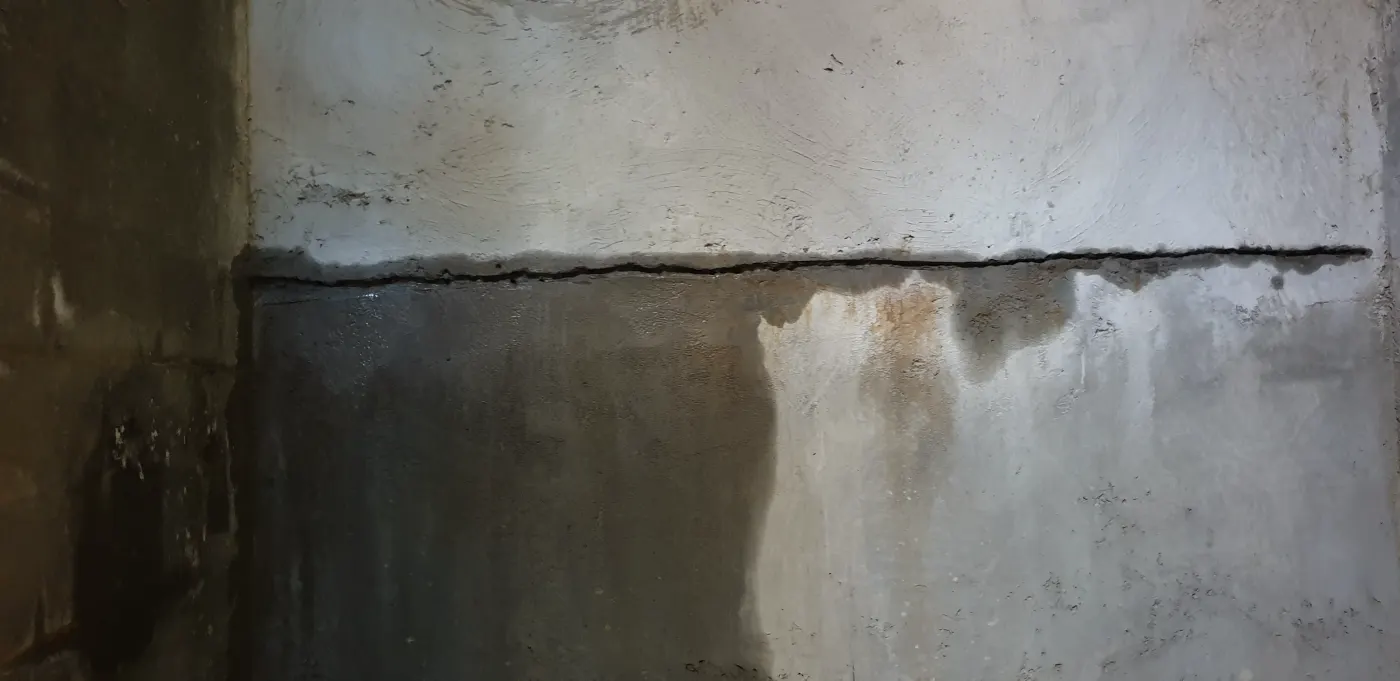 A construction joint in the basement wall with water bleeding out below it