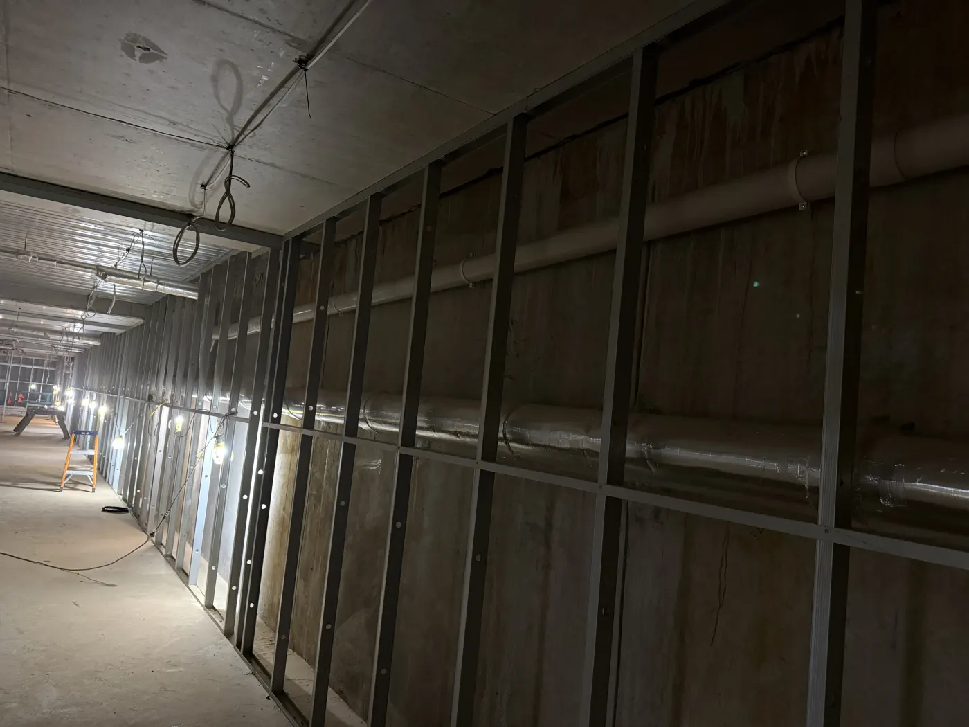 Bare basement wall behind stud framing, streaked where groundwater was tracking through the concrete