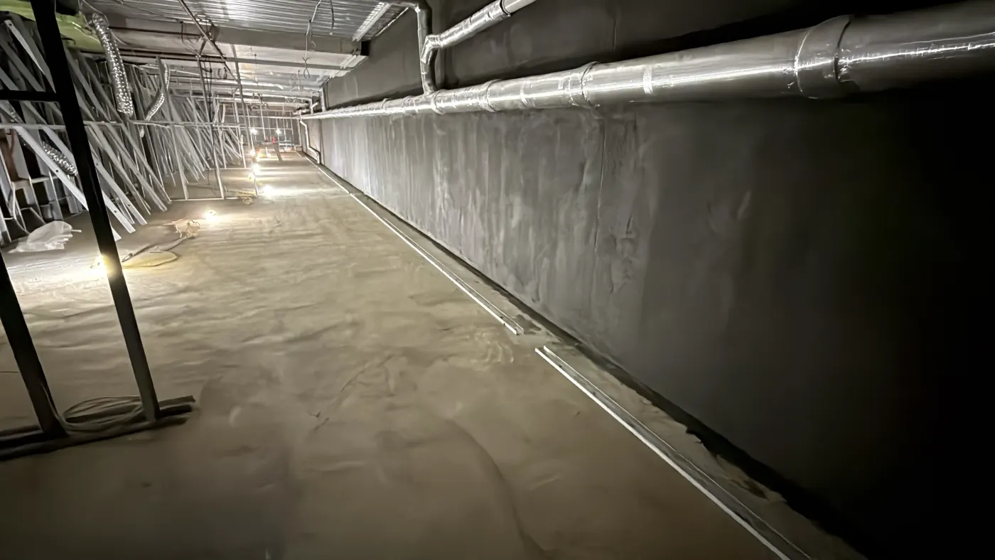 The same wall sealed from within, with the perimeter drainage channel installed and the floor made good