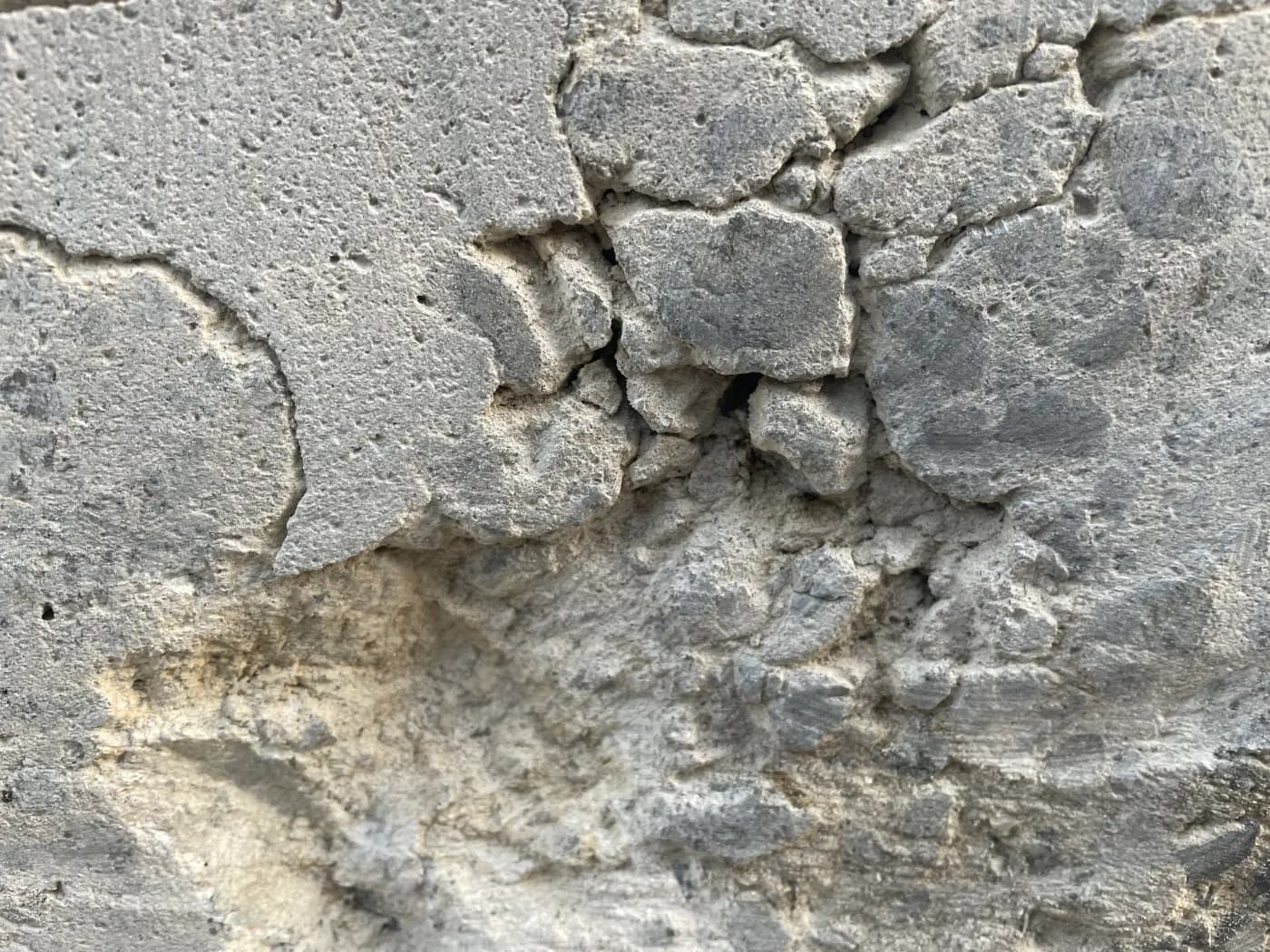 Spalled concrete broken away at the wall face