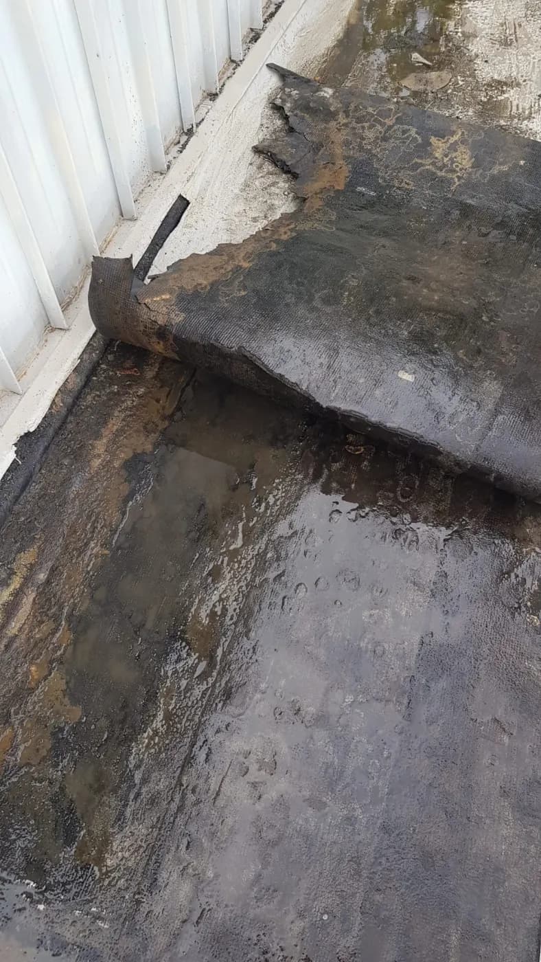 Water ponding on the deck against the wall, with no fall to a drain